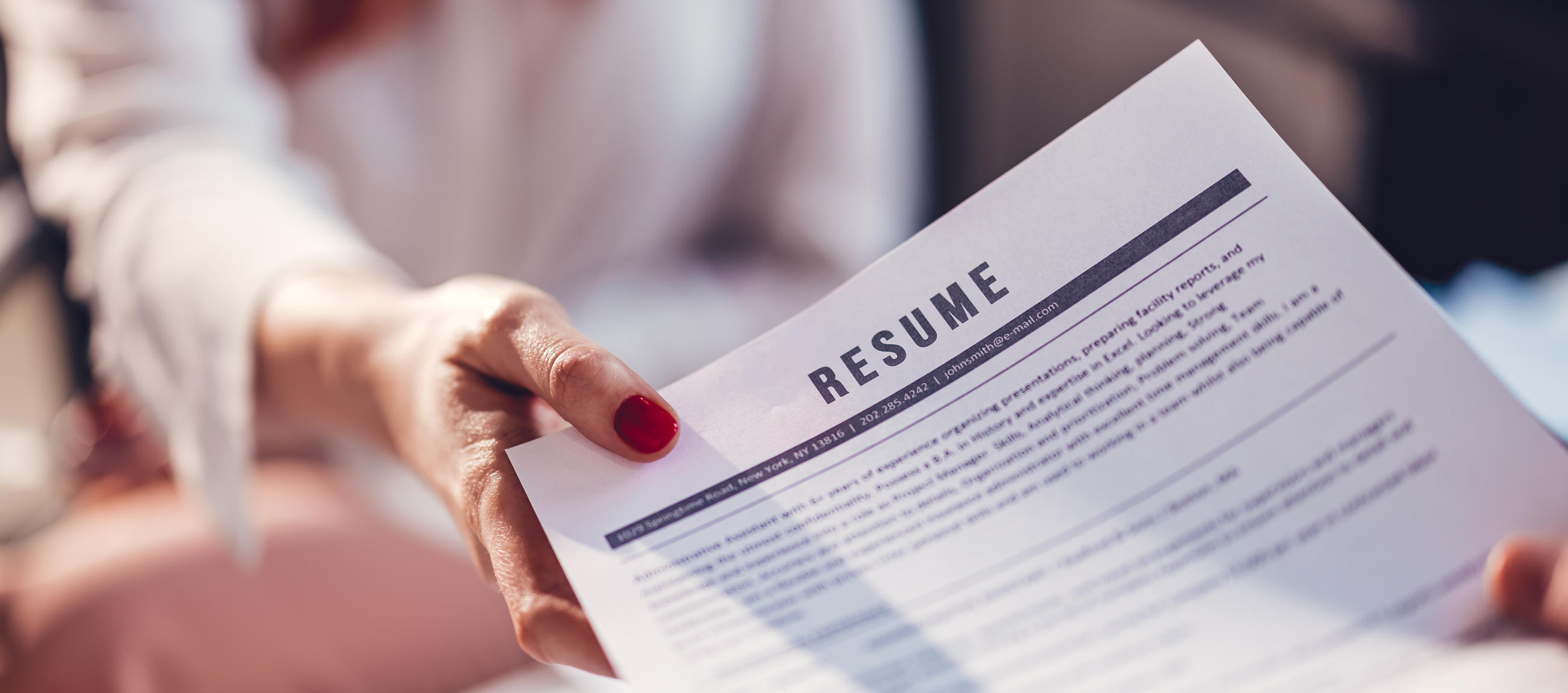 A person handing their résumé to another person